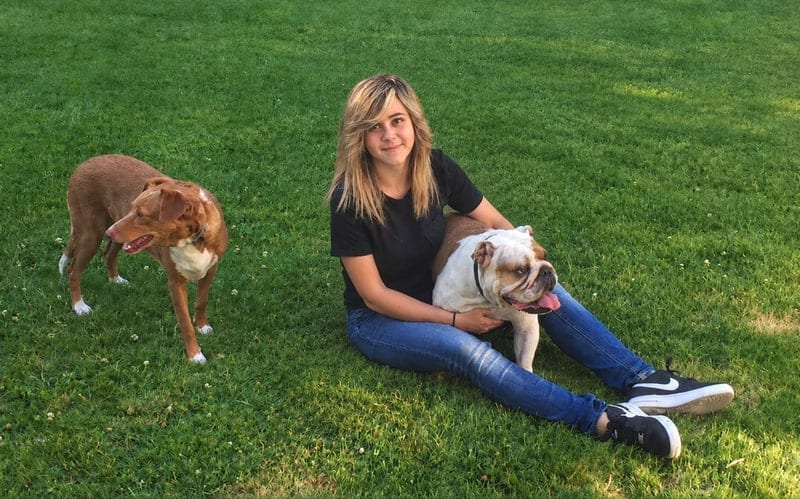María Isern sentada en el césped con dos perros